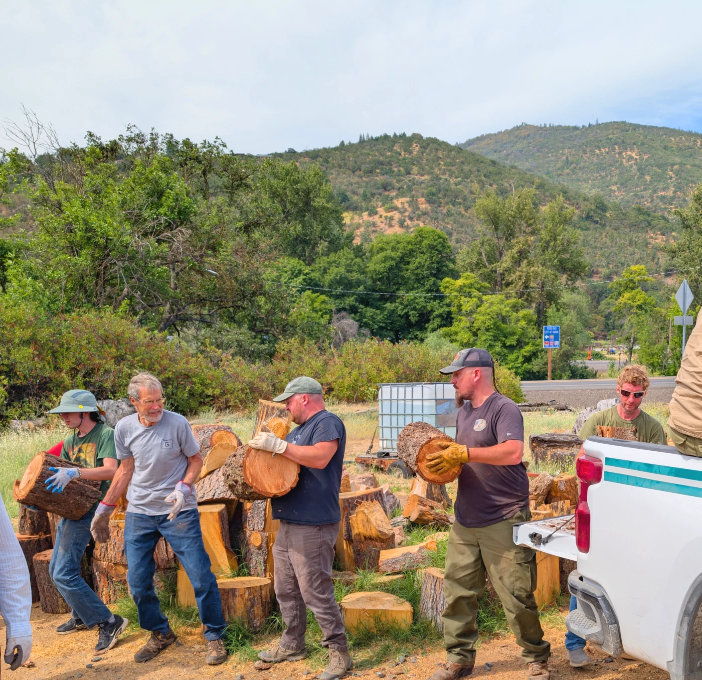 Volunteers work in a chain, unloading a truck by passing round pieces of wood down the chain.